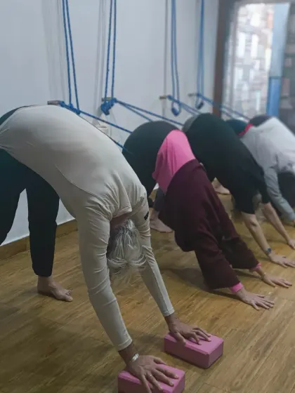 Practicing downward facing dog together, using blocks for support. This helps to elevate the hands, making the pose more accessible and allowing for a longer, straighter spine. Always be joyful.