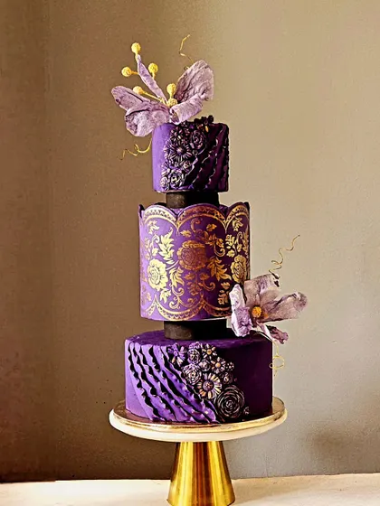 Inspired by the timeless beauty of a Banarasi saree, this three-tiered anniversary cake is a tribute to Indian artistry. The design features deep purple fondant with intricate gold stenciling, monochrome ruffles, and delicate wafer paper flowers. It’s a luxurious and unique creation for a truly special celebration.