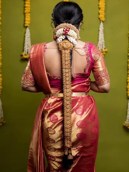 The bridal braid accessory, or jada, is a key part of the look. This one is a classic gold design that perfectly complements her temple jewellery set.