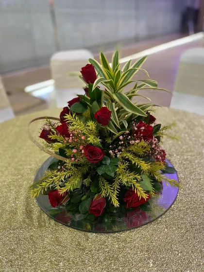 A simple yet elegant table centerpiece for a red-themed wedding. A small bouquet of red roses adds a touch of color and sophistication to the guest tables.