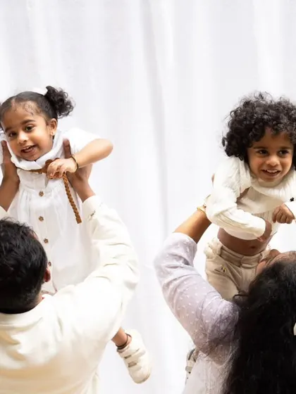 A beautiful moment with parents lifting their twin children in the air during an outdoor family photoshoot.