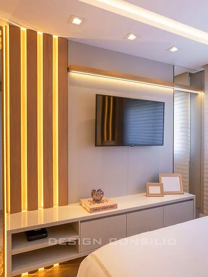 This TV unit design uses vertical wooden slats with integrated LED lighting to create a warm and modern feature wall. The floating white console provides storage while maintaining a light and airy feel.