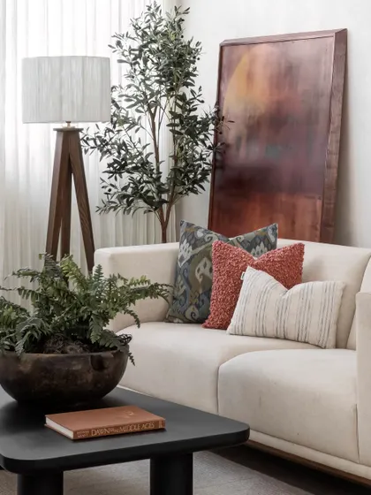 A quiet moment of modern elegance, grounded in natural textures. This serene nook invites you in with a plush ivory sofa, its softness elevated by vibrant, patterned cushions that add just the right pop of personality.