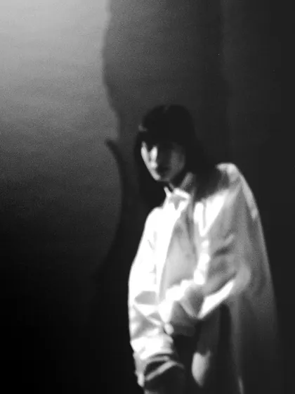 A blurry, atmospheric black and white portrait shot on film. The soft focus and deep shadows create a mysterious and dreamlike image, emphasizing mood over detail.