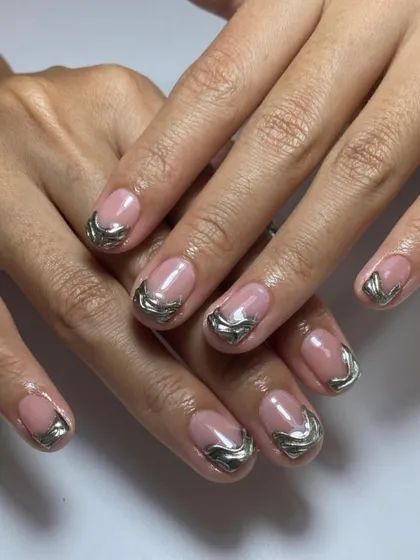 A unique take on the French manicure using sculpted silver chrome for the tips. This creates a "water droplet" or "molten metal" effect that is super trendy.
