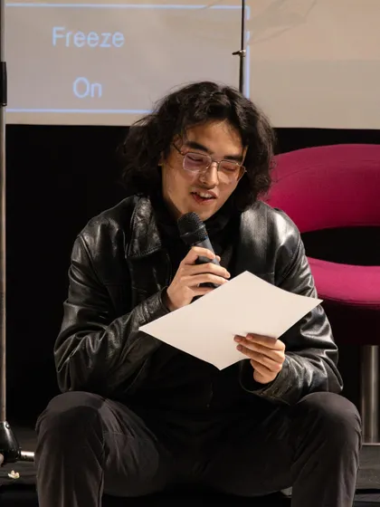 A participant reading his work during a relaxed moment in the showcase. Not all performances are high-energy; we help you find a style that is authentic to you.