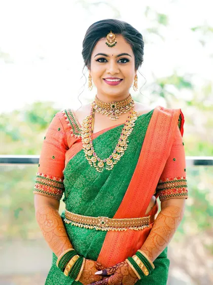 A full shot of the bride, looking absolutely stunning in her green and orange Kanjivaram saree.