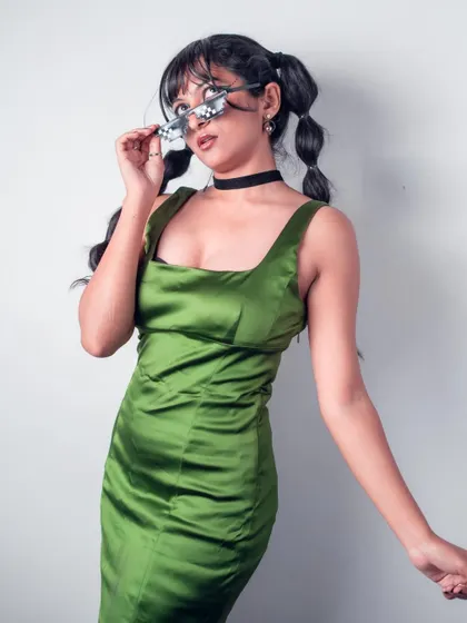 A playful pose in a green satin dress from the 'Art in Motion' series. The bubble pigtails and quirky glasses show my fun side and my skill in self-styling for creative shoots.