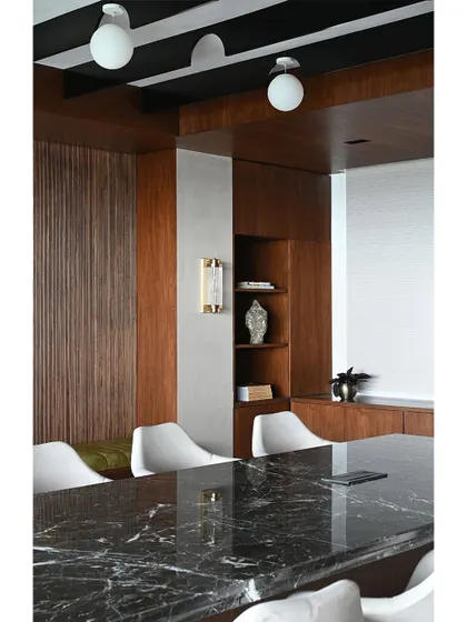 A close-up of the conference room's material palette, including the polished marble table, modern white chairs, and warm wood paneling.