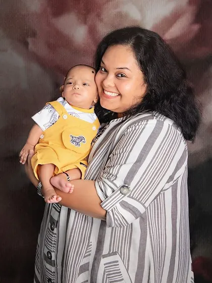 The pure joy of motherhood. This candid shot captures a mother's beautiful smile as she holds her baby boy, a simple and powerful expression of love.