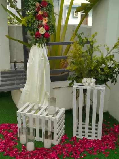 A daytime view of the decorative elements, including white wooden crates used as tables, candles, and floral arrangements on a green turf.