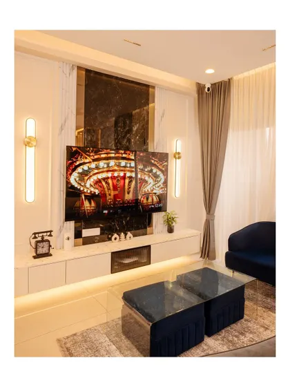 This TV unit features a large-format tile with a dark marble pattern, flanked by elegant wall sconces, creating a dramatic and high-end focal point.