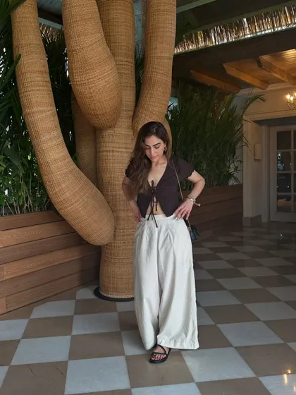 Unfiltered and unbothered on a beach vacay. This outfit with a black tie-front top and white pants is perfect for a brunch by the sea.