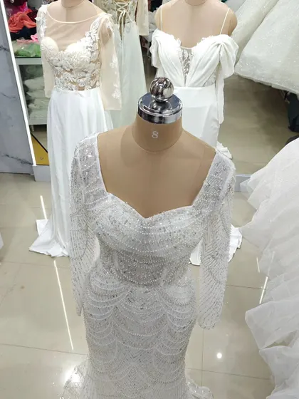 For the bride who loves glamour, this fully beaded white gown is a showstopper. The long sleeves and square neckline are covered in intricate pearl and sequin work, creating a look of pure opulence.
