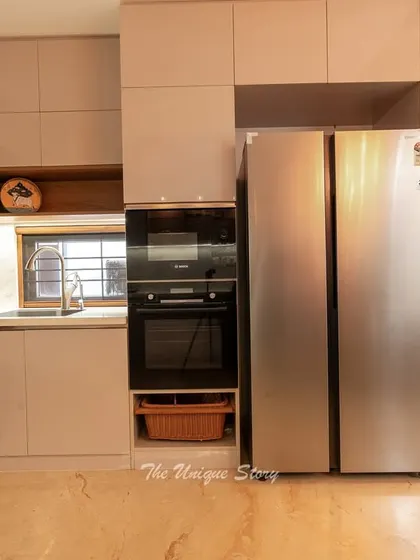 This shot highlights the appliance garage, with a built-in Bosch oven and a side-by-side refrigerator. A tall glass-front cabinet provides elegant storage for glassware, right next to the home's green courtyard.