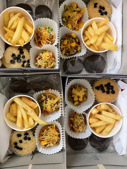 Party snack boxes with a fun mix of french fries, choco-chip muffins, mini pizzas, and chocolate cookies.