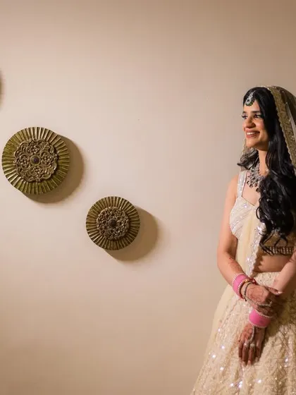 A smiling portrait of the bride, Manu, in her elegant white lehenga.