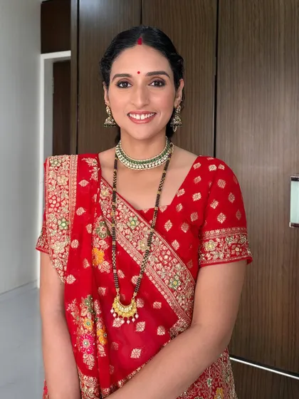 A classic festive look created for a Karwachauth celebration. The makeup features soft smokey eyes, a traditional red bindi, and a radiant complexion that complements the bright red saree.