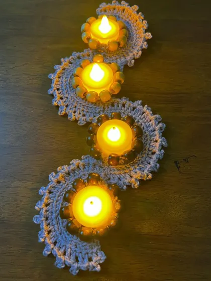 A full view of the four-light crochet runner, with alternating light and dark wooden beads. This piece makes a stunning centerpiece for a dining table during Diwali celebrations.