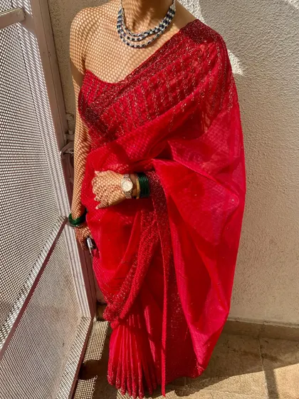 A beautiful client in a sheer red saree. The drape is kept light and airy to complement the delicate fabric, perfect for a daytime event.