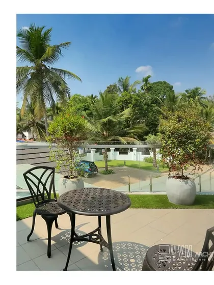 The balcony at Mannath House offers a private outdoor seating area with views of the surrounding greenery, perfect for enjoying a quiet morning.