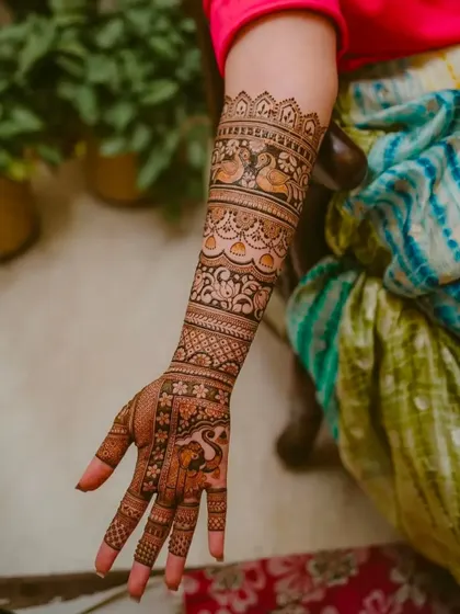 A full-arm design featuring bands of different traditional patterns, including swans and floral vines. The detail is consistent from the wrist to the elbow.