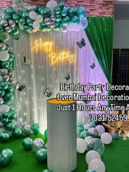 A refreshing green and white butterfly theme set up at home. The balloon arch is complemented by a sheer curtain with fairy lights and butterfly cutouts, creating a magical glow.