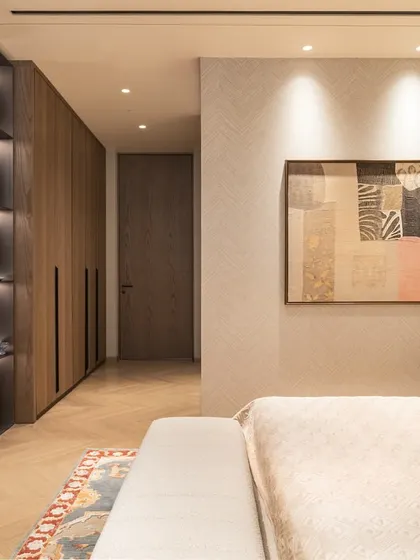 This view of the guest bedroom shows the custom dark veneer wardrobe and TV unit, which provide a rich contrast to the light walls and soft furnishings.