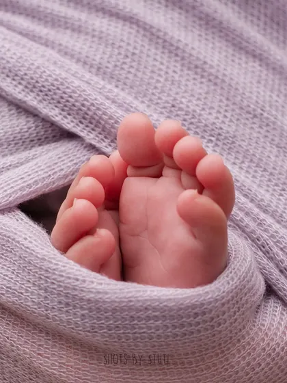A macro shot of tiny newborn feet peeking out of the swaddle. It’s these little details that make newborn photography so special.