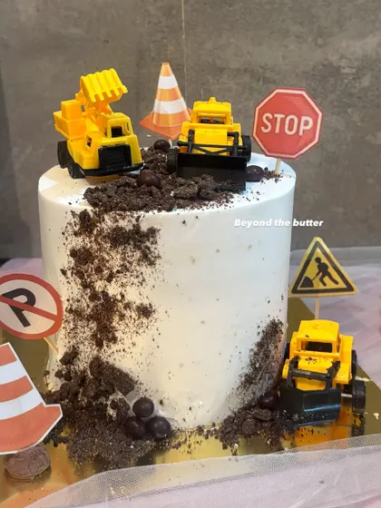 A construction theme cake for a little builder. I used crushed Oreo "dirt" and decorated the cake with mini toy trucks, traffic cones, and road signs for a fun and interactive design.