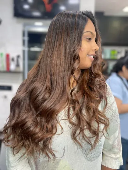 A stunning example of long, healthy hair styled in beautiful, cascading curls with a warm brown color.