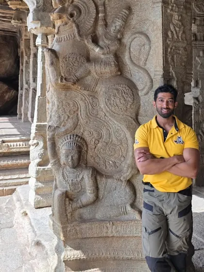 Posing next to a Yali pillar, a mythical creature often seen in the temple architecture of the Vijayanagara period.