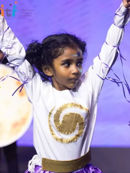 A girl dressed as a swirling galaxy performs with grace. The costumes are designed to be imaginative and expressive.