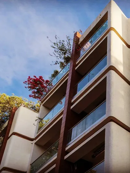 The facade of "The Humming Bird" apartment project in Bangalore. The design is characterized by a continuous, flowing line that creates a wave-like pattern, giving the building a unique and organic feel.