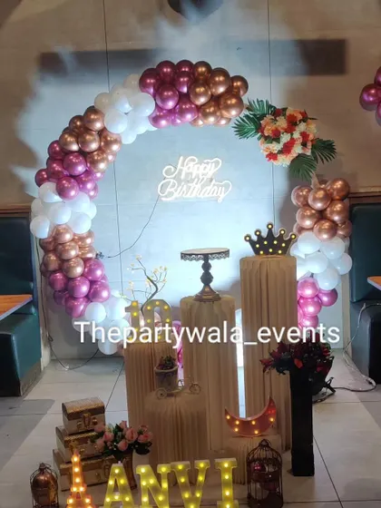 A rose gold, pink, and white balloon ring with a 'Happy Birthday' neon sign.