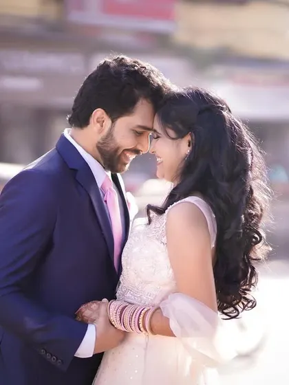A classic romantic pose in an urban setting. The couple's foreheads are touching as they share a quiet moment, beautifully framed by the city background.
