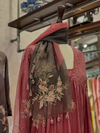 A close-up of another Kora piece, this time a dusty pink anarkali with a beautifully embroidered organza scarf draped around the neck.