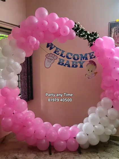 A simple "Welcome Baby" decoration with a pink and white circular balloon arch.