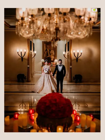 A grand, wide angle shot of the couple in the opulent lobby of The Leela Palace. Her makeup was designed to be impactful even from a distance, ensuring she looked stunning in every frame.