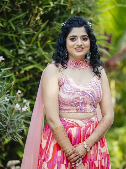 A close-up of the Haldi look. The makeup is light and fresh, with a focus on dewy skin, and her curly hair is adorned with a small hairpiece.