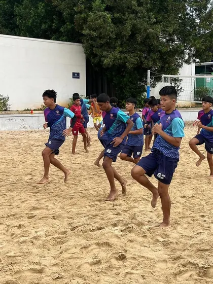 Players engaged in dynamic warm-ups on the sand before a tough fitness session.