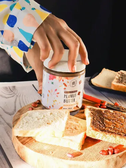 Another lifestyle shot for the peanut butter brand, this time with a hand reaching for the jar. This creates a sense of action and desire, making the product feel more dynamic and appealing.