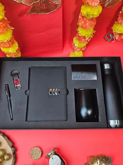 A sleek and modern Diwali corporate gift set. This all-black ensemble includes a combination lock diary, a wine-style tumbler, a water bottle, and other accessories, ready for your branding.