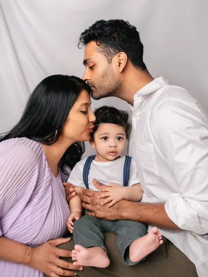 A loving family portrait. The parents' adoring kisses and the baby's curious gaze towards the camera make this a perfectly balanced and emotional shot.