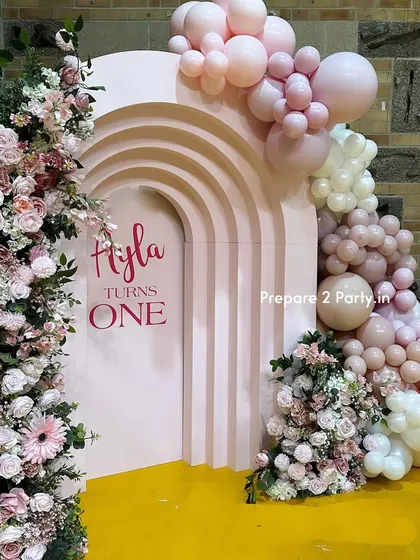 These images highlight the unique elements of this first birthday, including the custom-designed cake plinth and the combination of fresh flowers and balloons for a high-end look.