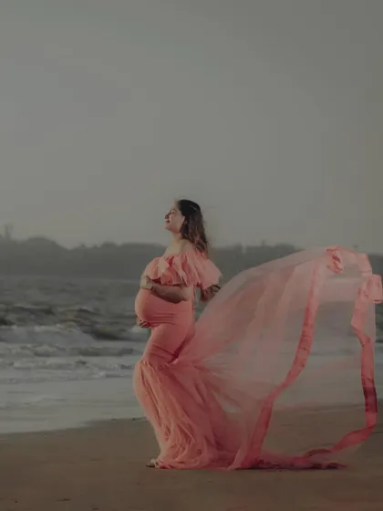 This peach mermaid gown looks stunning against the sea, with its long train flowing in the breeze. It's a perfect choice for a dreamy and romantic beachside maternity shoot.