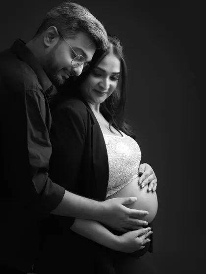 A close-up on connection. This intimate black and white portrait captures the gentle way he holds her and the baby bump, focusing on their loving bond.