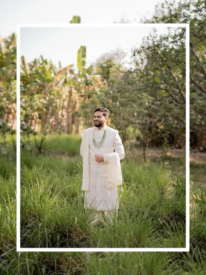 A full-length portrait of the groom standing in a field of tall green grass, looking happy and relaxed.
