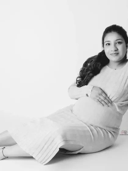 A simple and pure black and white portrait of a mom-to-be. The high-key lighting creates a soft and angelic feel, focusing on her gentle expression and baby bump.