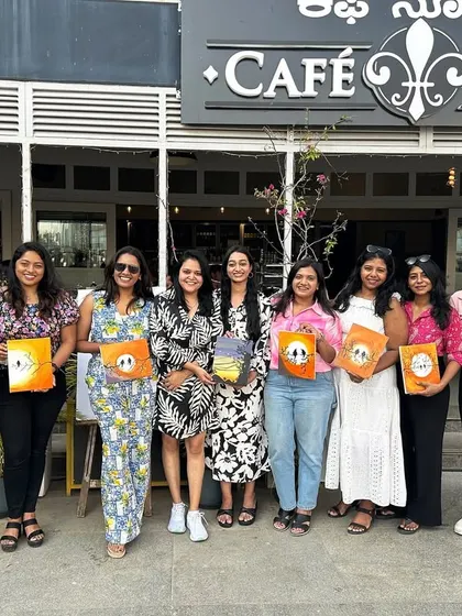 A great group photo outside the cafe venue, with everyone holding up their finished paintings.
